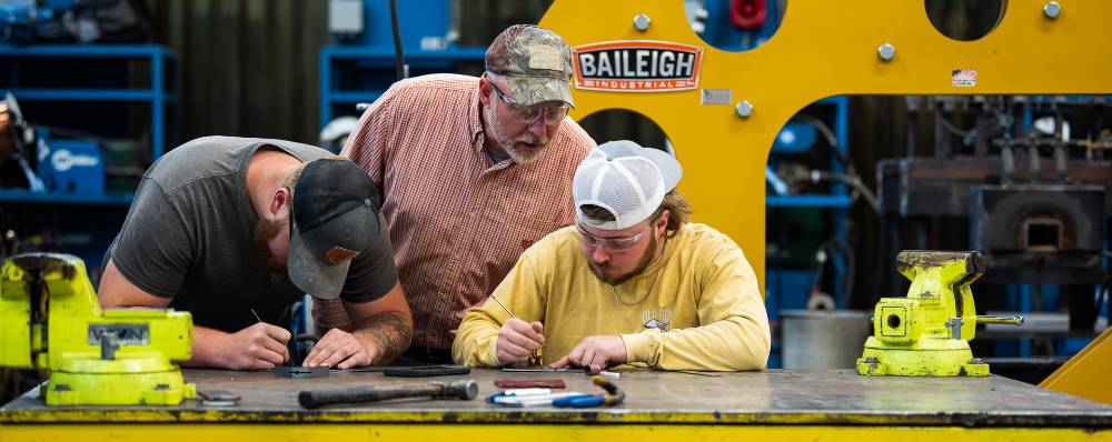 two students getting instruction from welding teacher