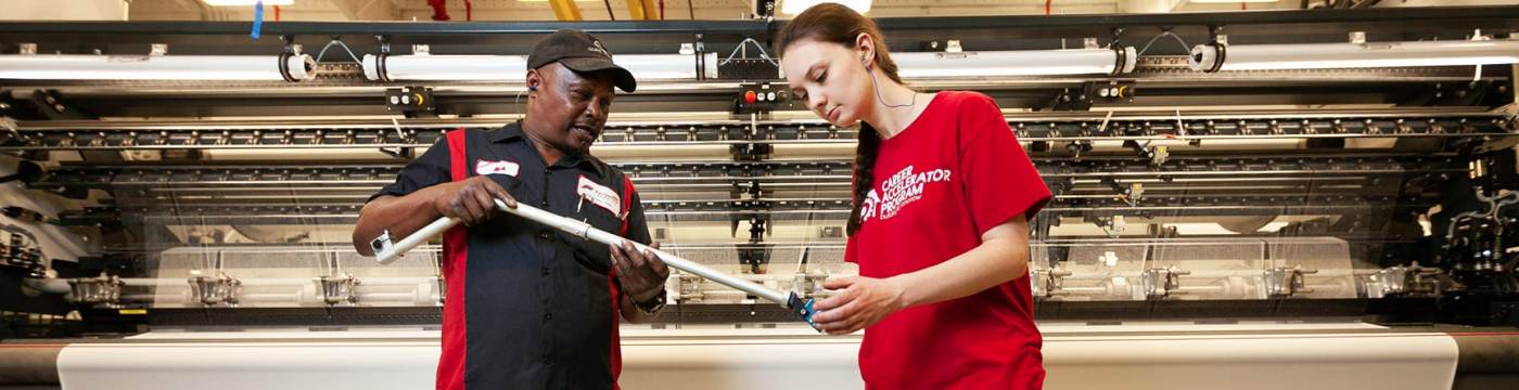 young apprentice being taught by employeer on machine