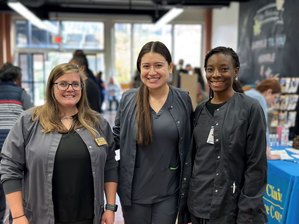 three medical assisting students smiling at camera