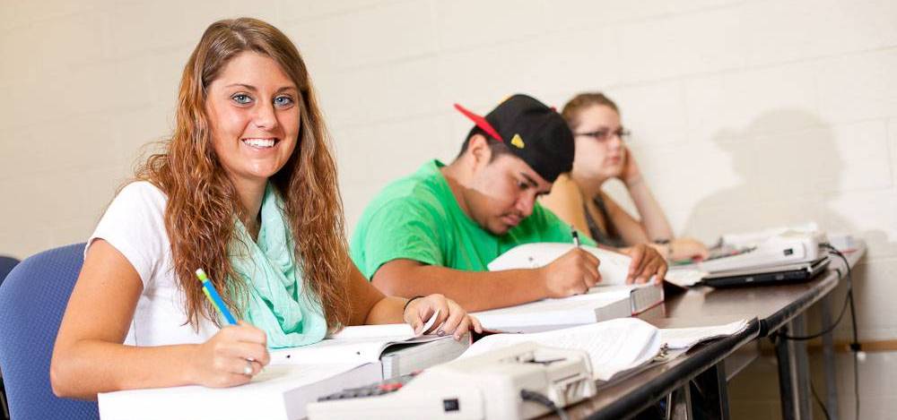 college student sitting at desk writing on paper