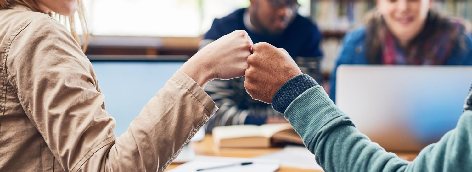 two young student giving each other a fist bump for a sign of support.