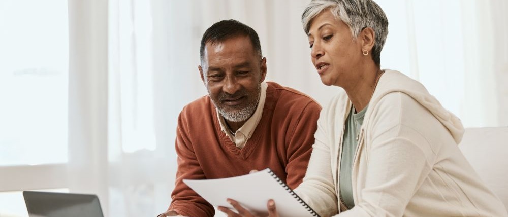 two senior citizens sitting on couch looking at computer